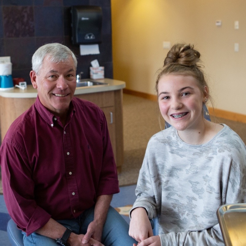 orthodontist-billings-mt-001 Orthodontist Dr. Thomas Kovacs with a teenage patient smiling, showcasing braces in a welcoming office setting, emphasizing Billings orthodontics and personalized care for achieving ideal smiles.